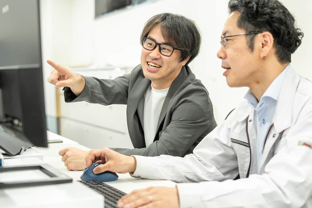 オフィスでモニターを見ながら議論する社員